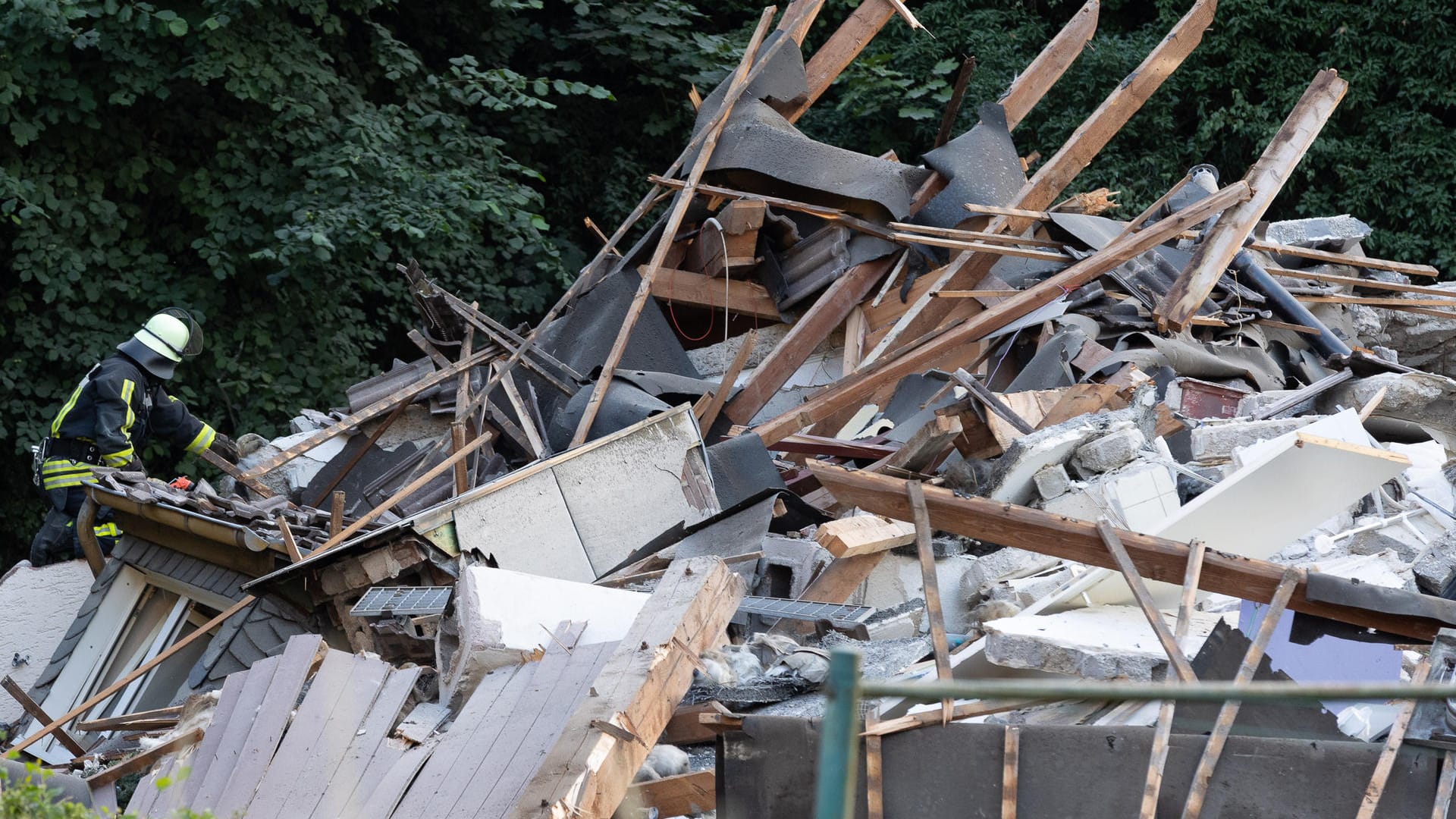 Ein Feuerwehrmann steht auf den Trümmern des eingestürzten Hauses: Einige Menschen gelten noch als vermisst.