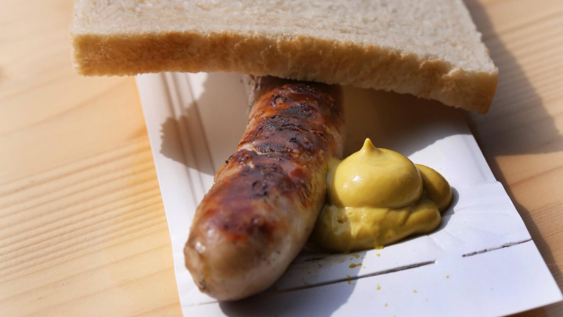 Eine Bratwurst mit Senf und Brotscheibe