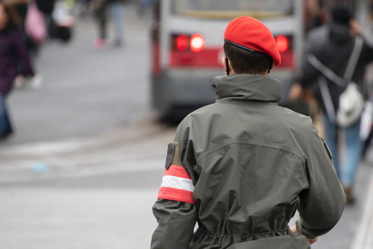 Ein Soldat des österreichischen Bundesheeres läuft uniformiert durch eine Fußgängerzone.