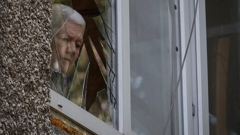 Eine Frau im Donbass schaut durch ein zerbrochenes Fenster: Das Kriegsgeschehen in der Ukraine flacht keineswegs ab.