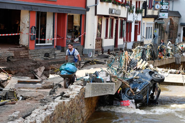 Ein Helfer befördert in Bad Münstereifel Müll und Trümmer: Das Hochwasser der Erft verwüstete den historischen Kern der Stadt komplett.