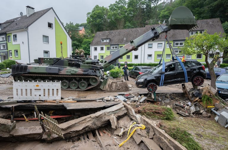 Soldaten der Bundeswehr bergen mit einem Pionierpanzer ein zerstörtes Auto in Hagen: Teile der Stadt waren so stark betroffen, dass zunächst die Feuerwehr nicht mehr zu den Unglücksorten durchkam.