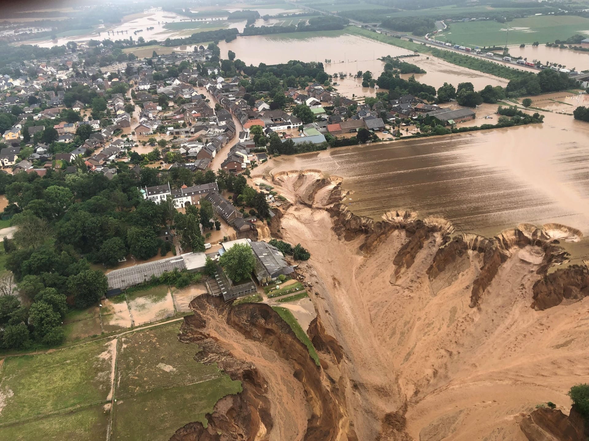 Ein Luftbild zeigt einen gewaltigen Erdrutsch in Erftstadt-Blessem an einem Tagebau: Gegen die Eigentümer und Verpächter der Kiesgrube wird ermittelt.