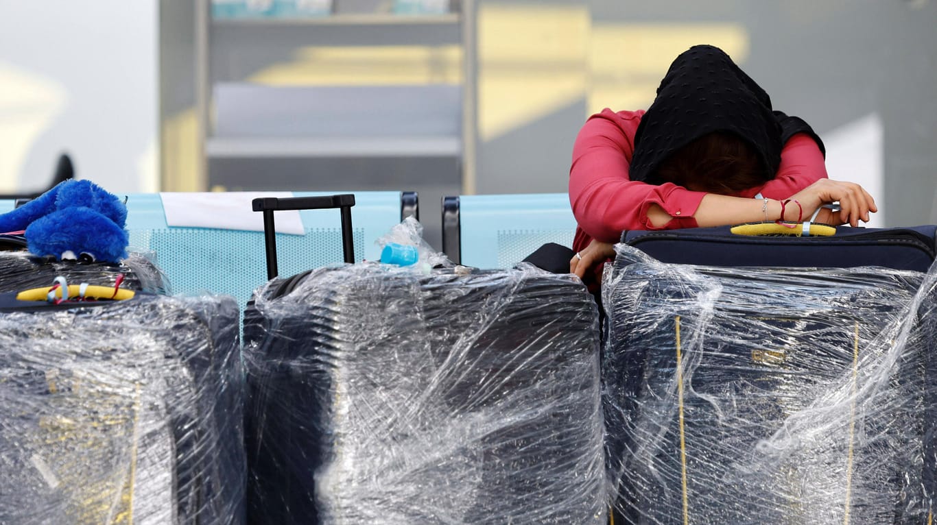 Eine erschöpfte Reisende am Flughafen Köln-Bonn. Passagiere müssen dort mehrere Stunden auf Check-In oder vor Sicherheitskontrollen warten.