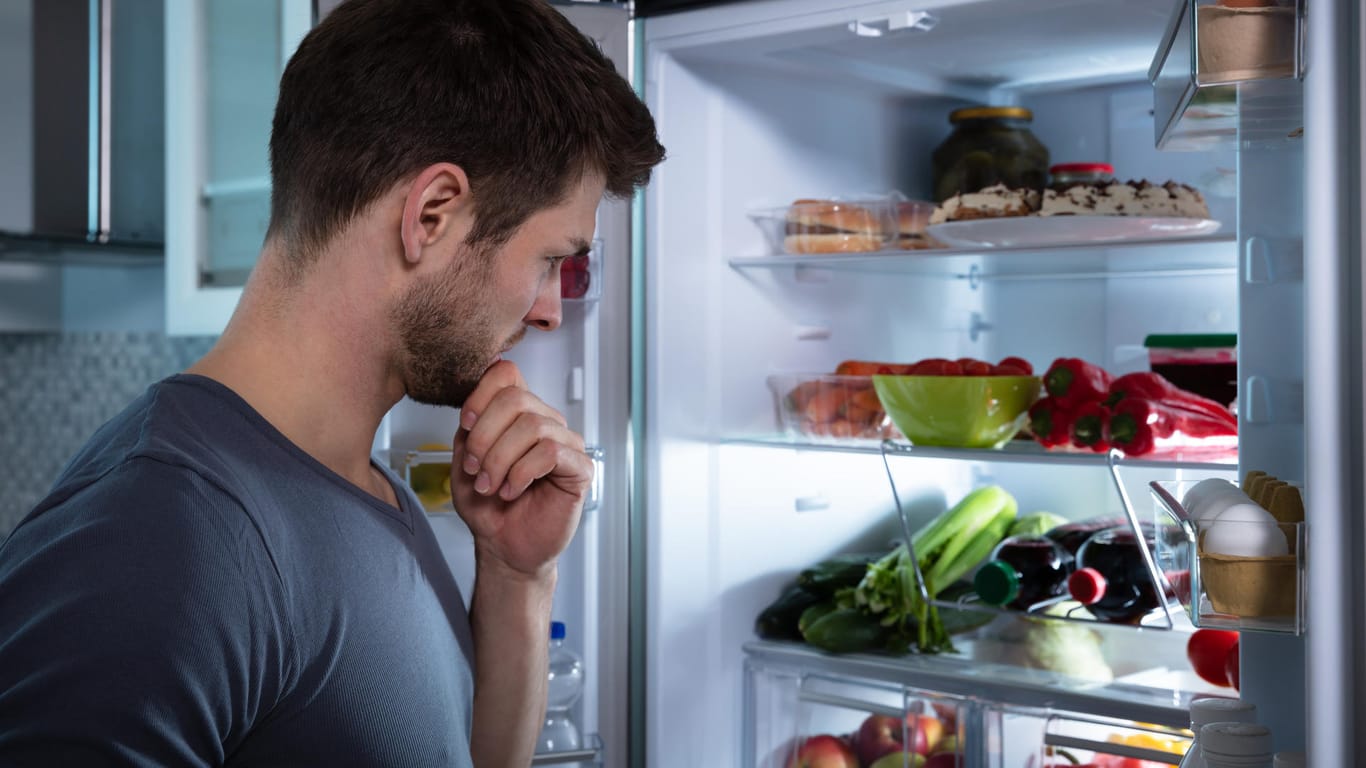 Ein Mann schaut in den Kühlschrank.