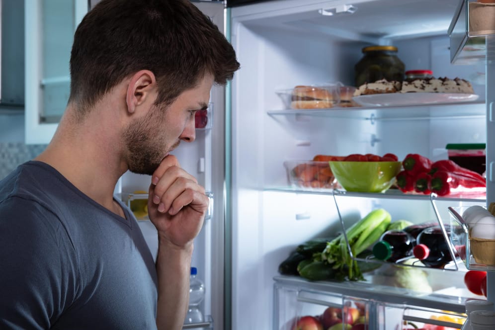 Ein Mann schaut in den Kühlschrank.