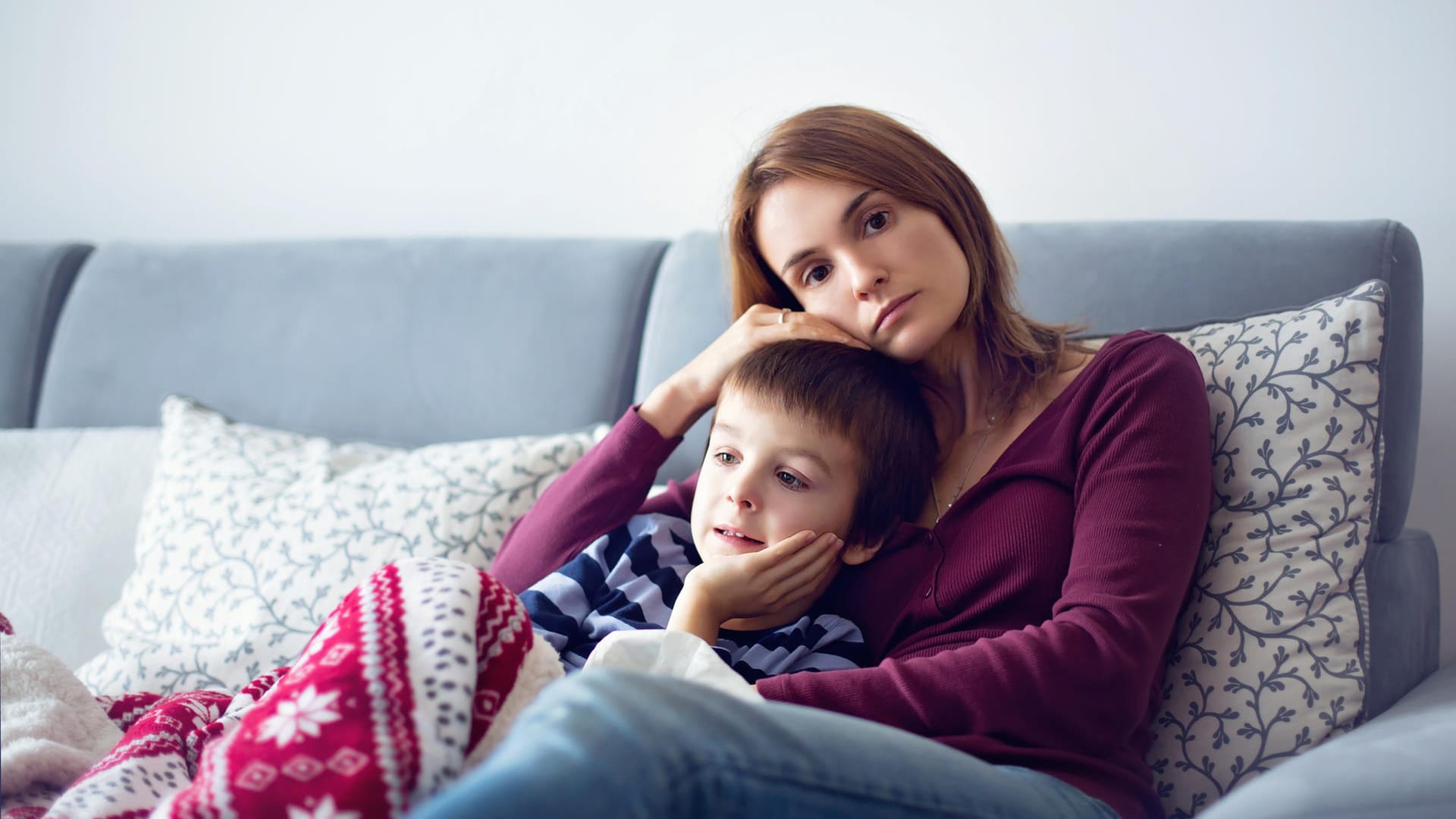 Nachdenklich aussehende Mutter mit Jungen auf dem Sofa.