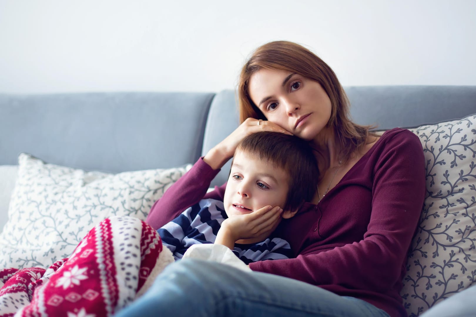 Nachdenklich aussehende Mutter mit Jungen auf dem Sofa.