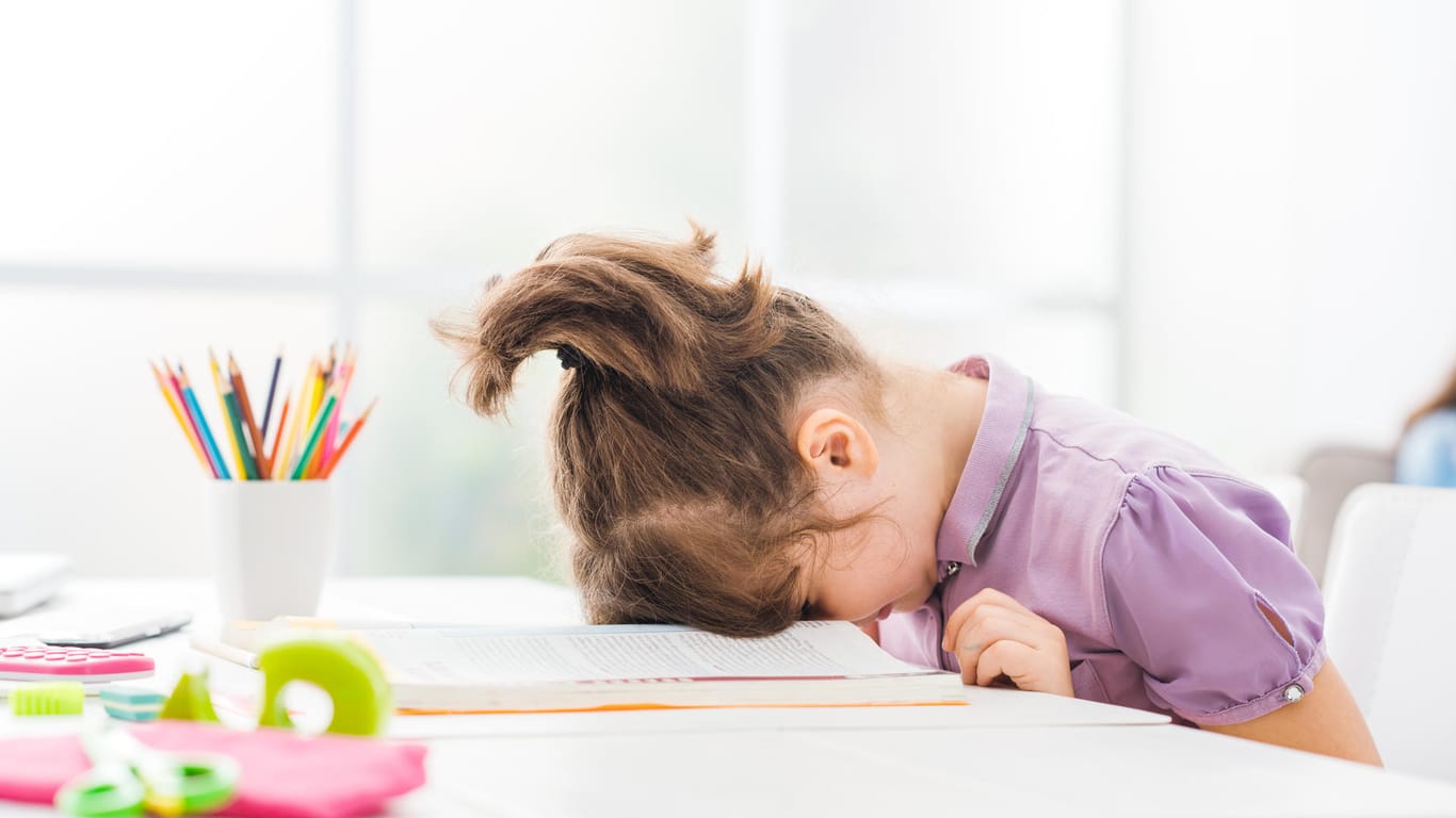 A girl puts her head on the desk.