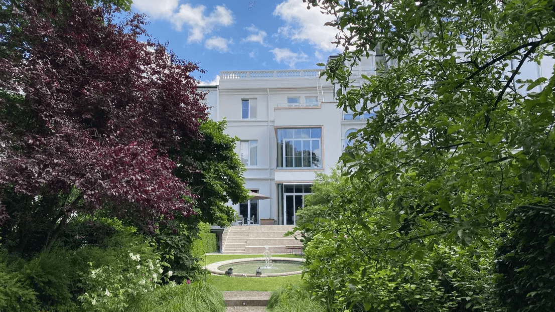 Blick aus dem Garten mit Springbrunnen auf eine Stadtvilla in Hamburg.