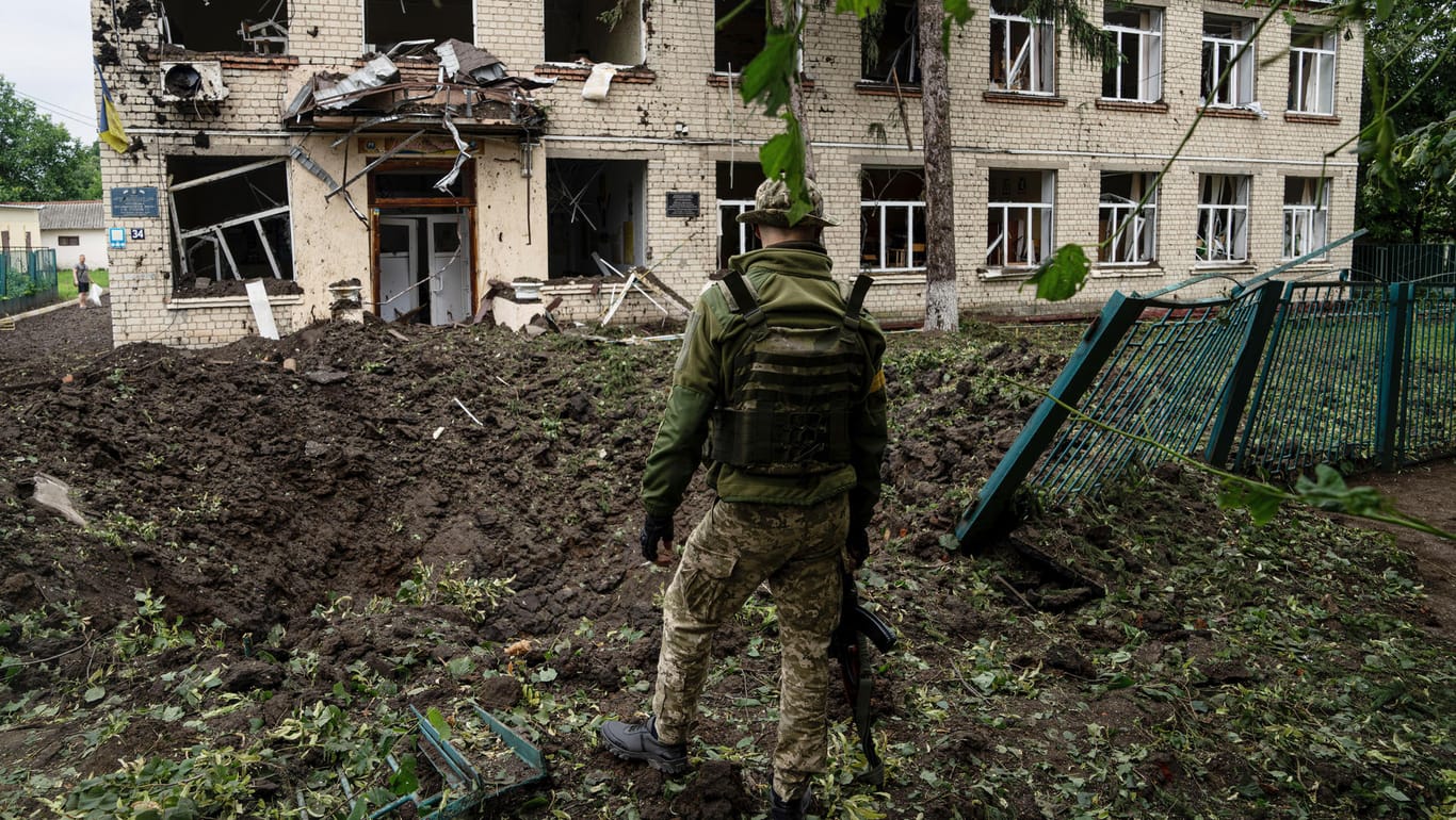 Tschuhujiw: Ein ukrainischer Soldat steht vor einem Schulgebäude, das durch Beschuss des russischen Militärs beschädigt wurde.