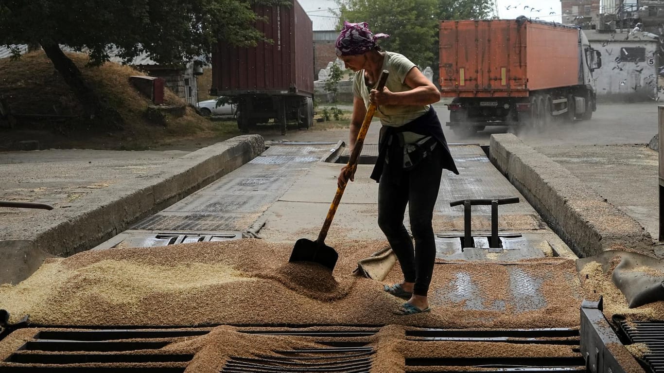Ein Arbeiter in Melitopol reinigt Getreide vom Boden (Symbolbild): Russland hat kurz nach Beginn der Militäroperation in der Ukraine die Kontrolle über einen Teil der Region Saporischschja übernommen.