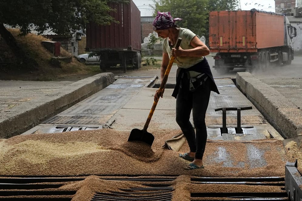Ein Arbeiter in Melitopol reinigt Getreide vom Boden (Symbolbild): Russland hat kurz nach Beginn der Militäroperation in der Ukraine die Kontrolle über einen Teil der Region Saporischschja übernommen.