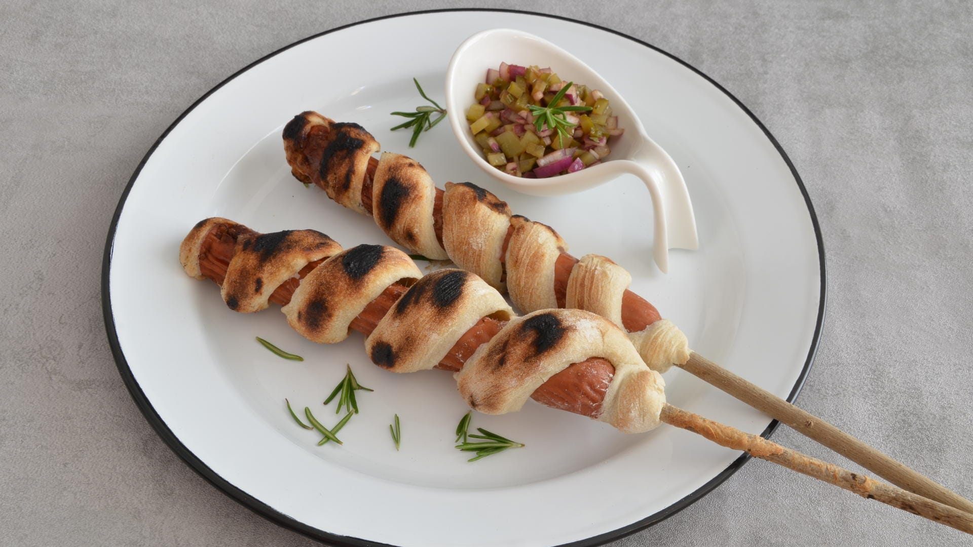 Stockbrot à la Hotdog: Das Stockbrot wird schlangenmäßig um den Hotdog gewickelt und gegrillt.