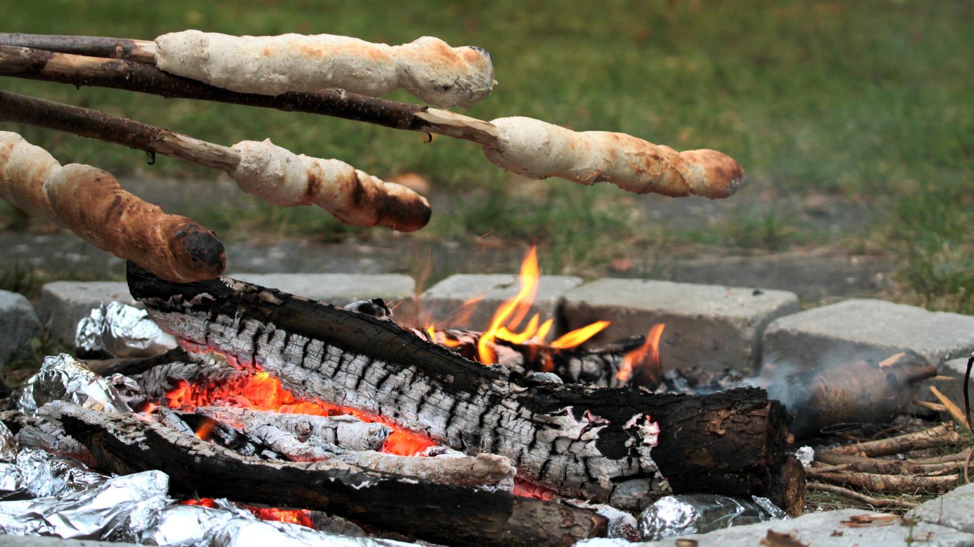 Stockbrot über einem Feuer backen: Wer in der Öffentlichkeit Feuer machen will, muss sich an bestimmte Vorgaben halten.