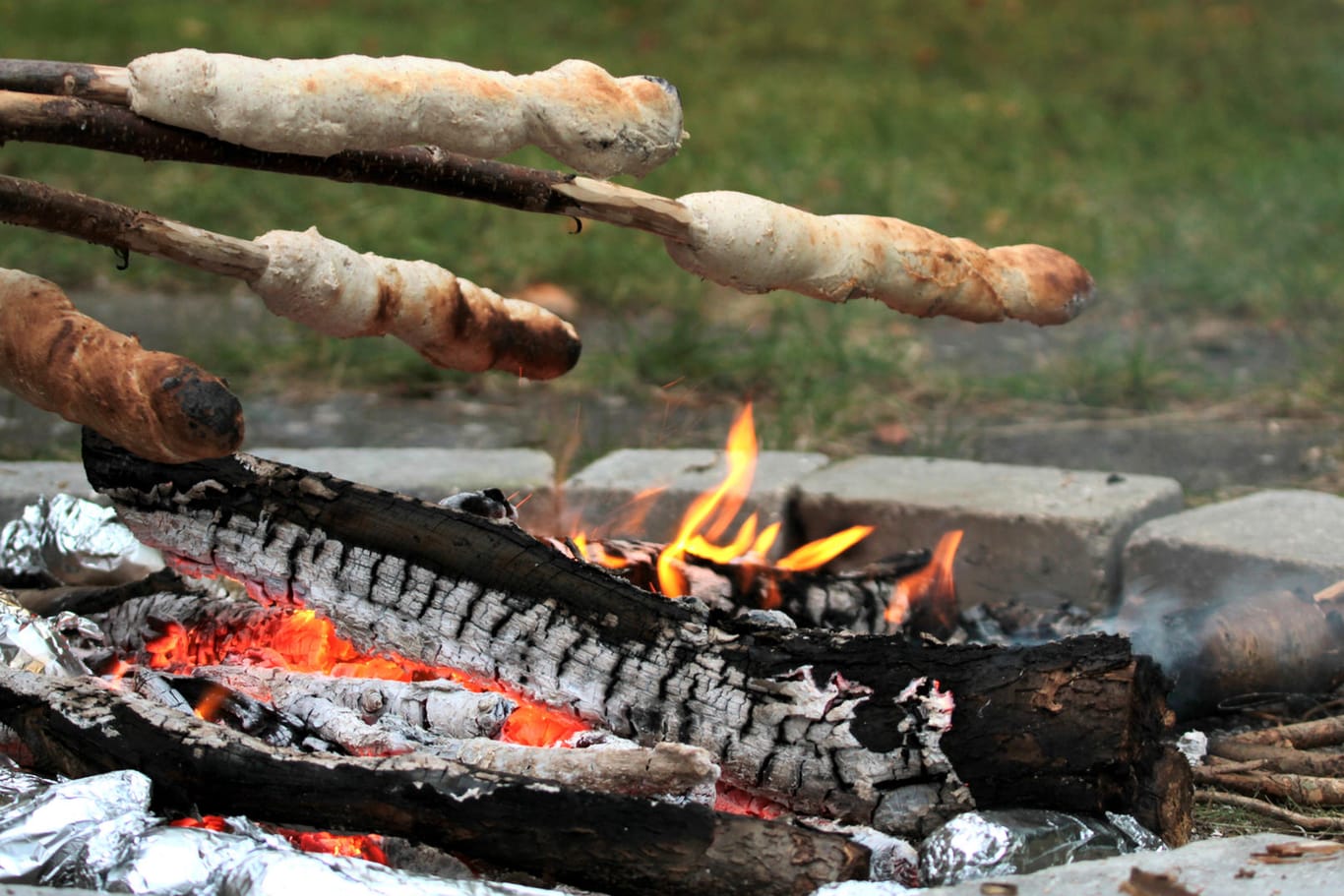 Stockbrot über einem Feuer backen: Wer in der Öffentlichkeit Feuer machen will, muss sich an bestimmte Vorgaben halten.