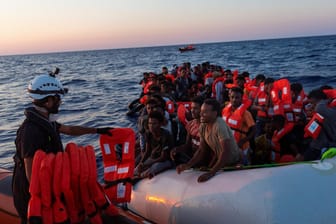 Ein Mitglied der "Sea-Watch" verteilt Rettungswesten an Migranten: Seit Jahresbeginn sind 34.000 Migranten über das Mittelmeer nach Italien gelangt.