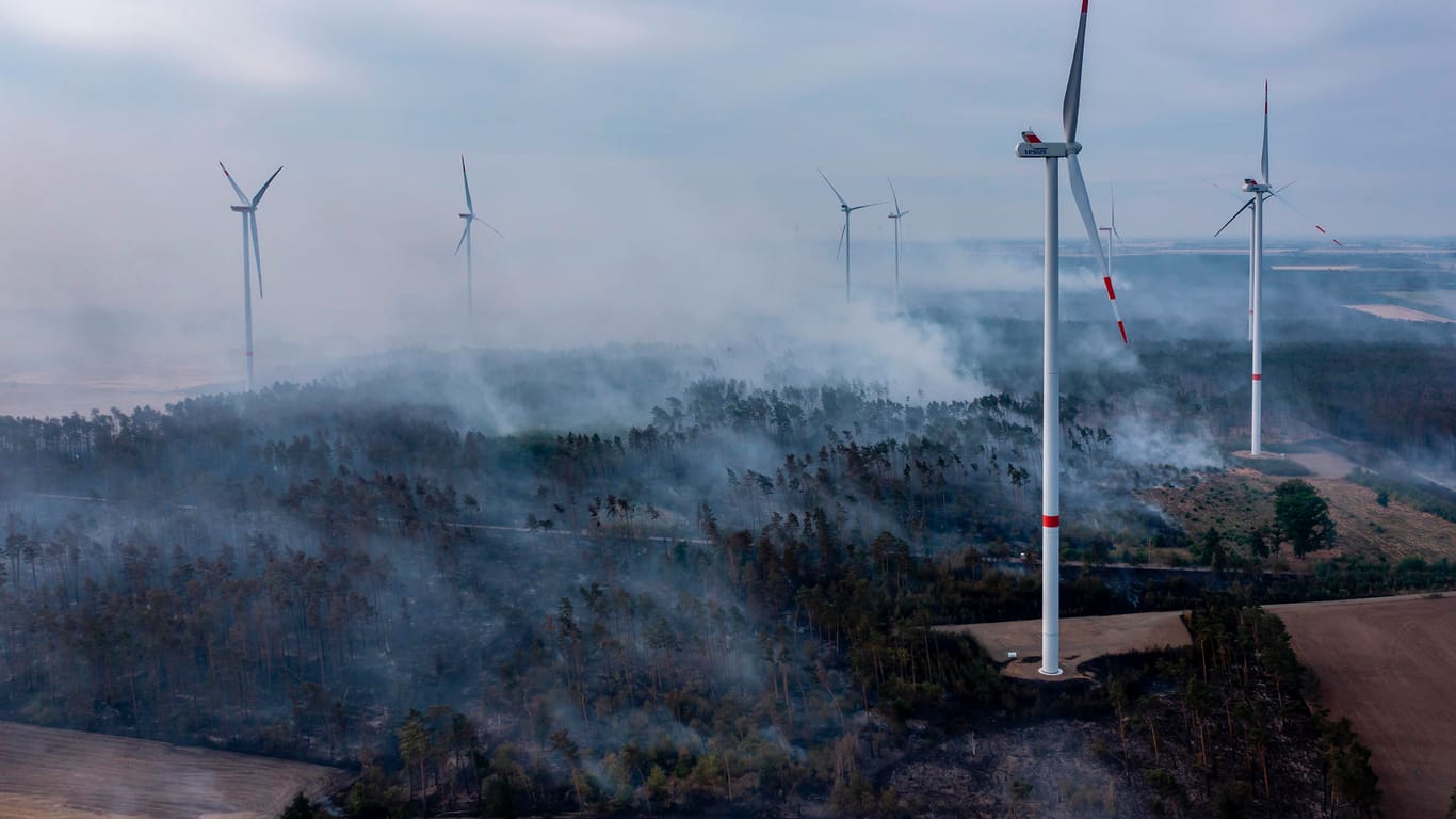 Rauchschwaden ziehen bei einem Waldbrand zwischen Windkraftanlagen über ein Waldgebiet im Landkreis Elbe-Elster: Der Brand weitet sich weiter aus.