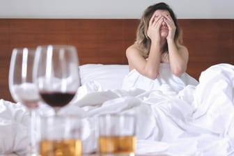 Junge Frau mit Kater im Bett: Der Genuss von Alkohol kann schon nach kürzester Zeit eine Migräne auslösen.