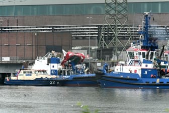 Der Schlepper liegt neben einem Polizeischiff im Hafen.