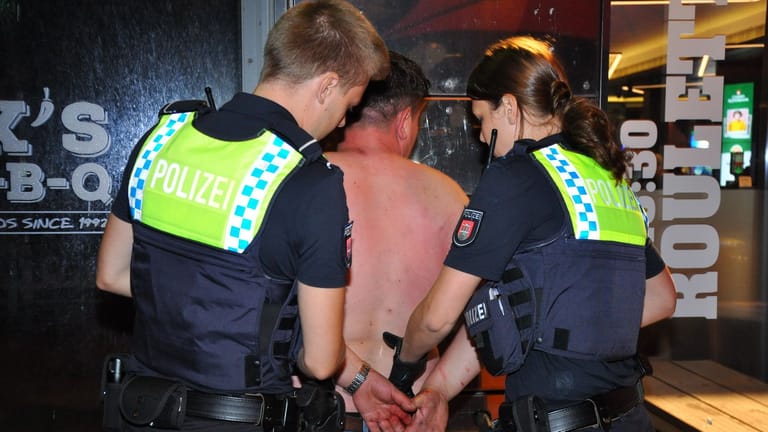 Die Einsatzkräfte legen einem der Beteiligten Handschellen an: In der Nacht ist es zu einer Schlägerei zwischen vier Männern auf der Reeperbahn in Hamburg gekommen.
