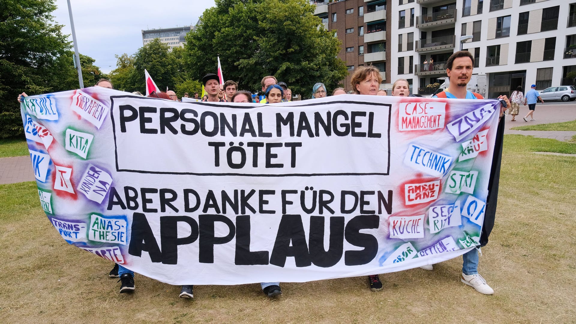 Streikende Klinik-Mitarbeitende halten ein Transparent mit der Aufschrift: "Personalmangel tötet - aber danke für euren Applaus".