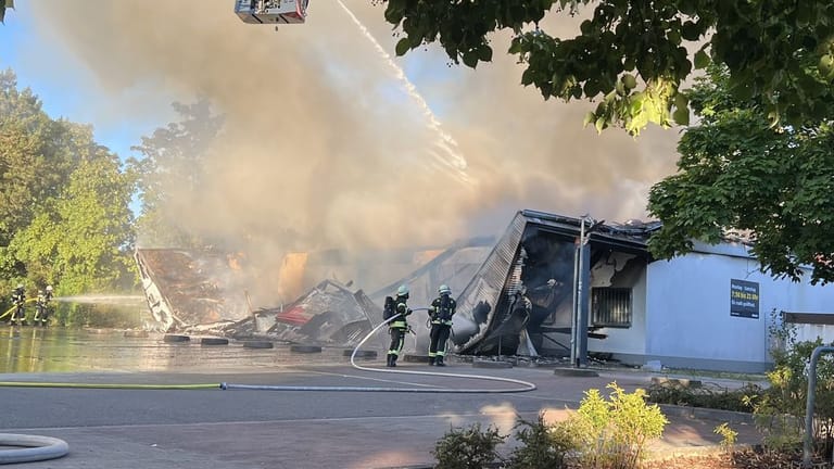 Feuerwehrleute bei Löscharbeiten: Das Dach des Supermarkts stürzte ein.