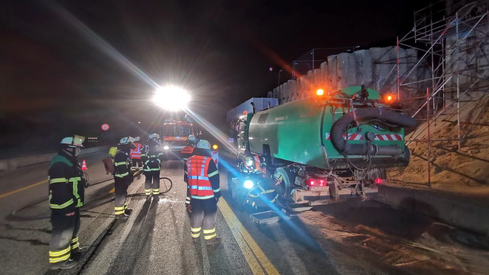 Einsatzkräfte der Feuerwehr stehen neben der Kehrmaschine.