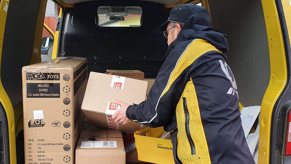 Ein Mitarbeiter der Post holt ein Paket aus einem Lieferwagen (Symbolbild):