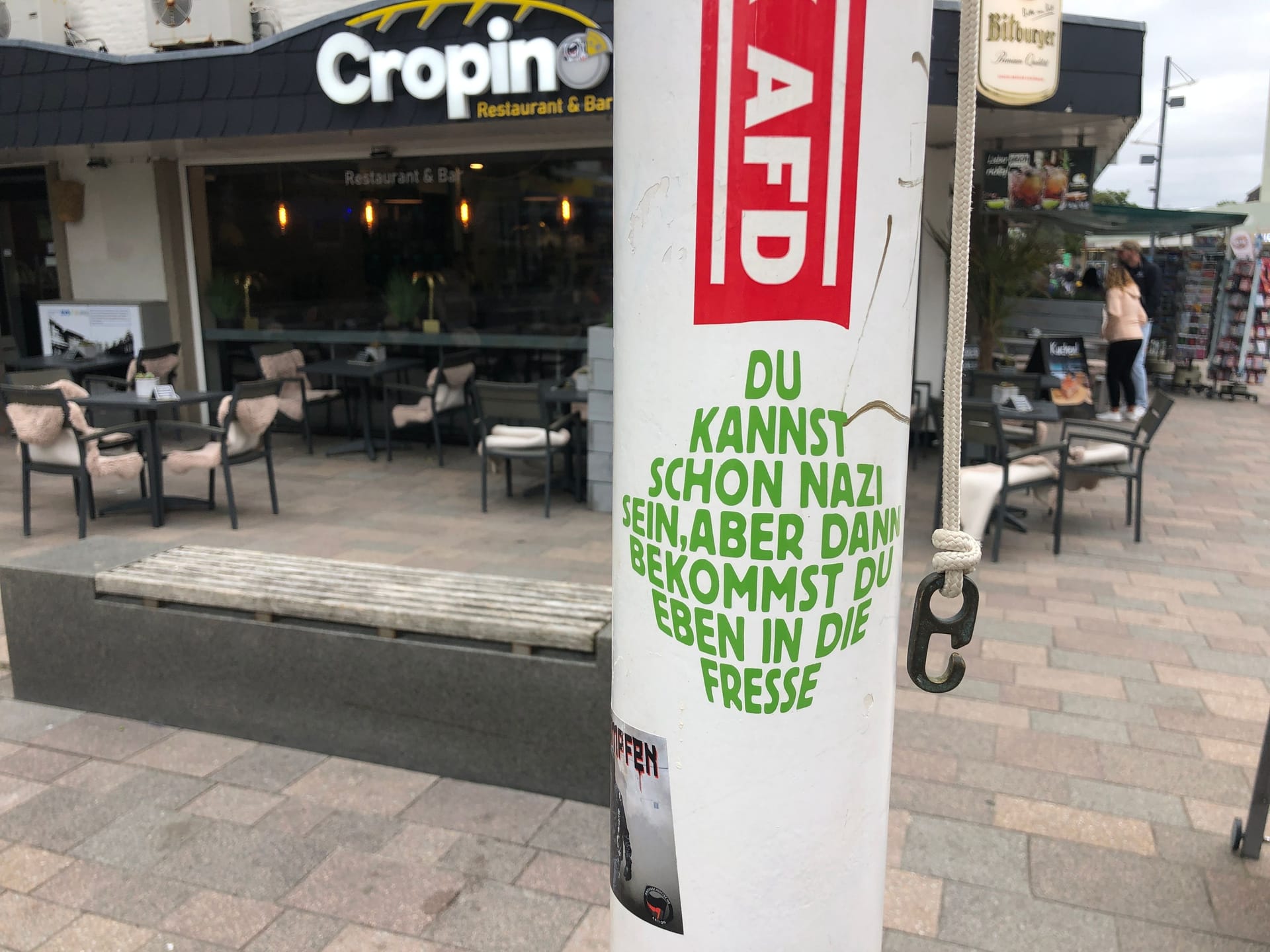 Ein mit Stickern beklebter Fahnenmast an der Wilhelmine in Westerland: Aufkleber wie dieser mit Sprüchen wie "Du kannst schon Nazi sein. Aber dann bekommst du eben in die Fresse" sind besonders in der Friedrichstraße häufig zu sehen.