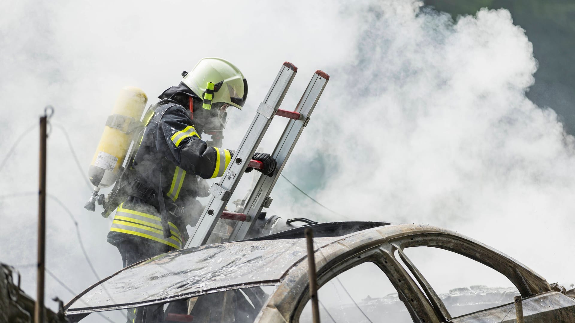 Ein Feuerwehrmann löscht ein brennendes E-Auto (Symbolbild): Auch die Berliner Feuerwehr rückt immer öfter zu solchen Einsätzen aus.