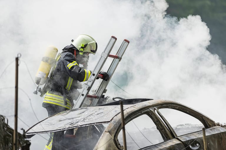 Ein Feuerwehrmann löscht ein brennendes E-Auto (Symbolbild): Auch die Berliner Feuerwehr rückt immer öfter zu solchen Einsätzen aus.