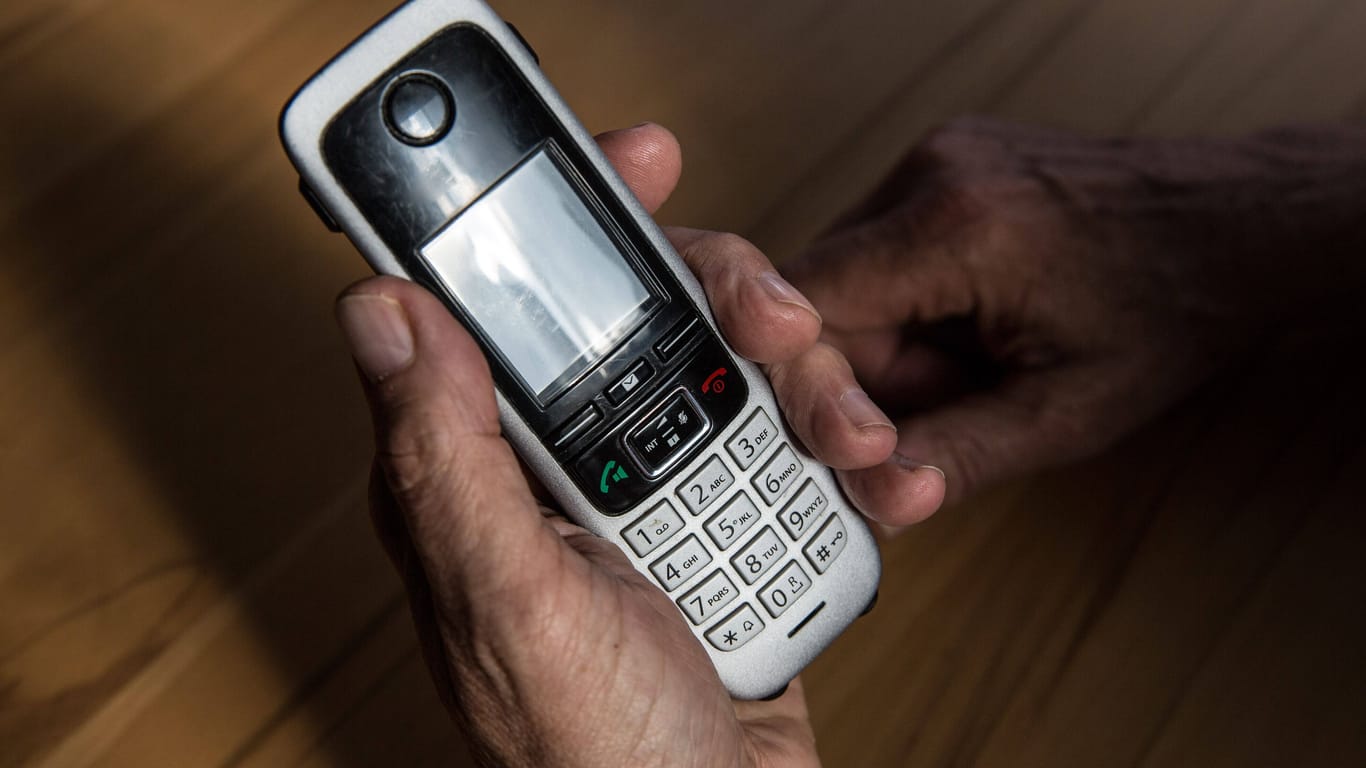 Die Hand eines älteren Menschen hält ein Telefon, Mobilteil in der Hand (Archivbild): In Dortmund ist ein Senior um 200.000 Euro betrogen worden.