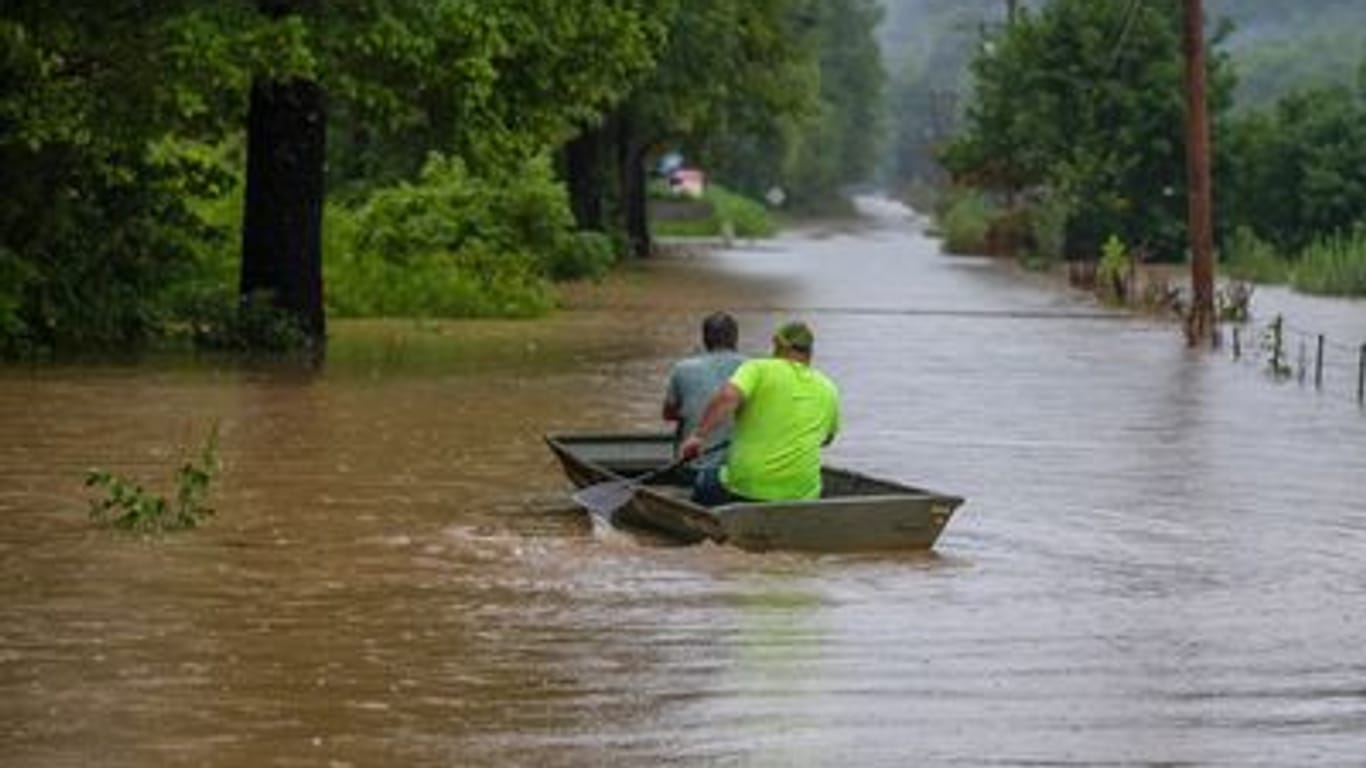 Zwei Männer fahren in einem Boot über eine überschwemmte Straße: Nach heftigen Regenfällen in Kentucky mit Sturzfluten und Schlammlawinen befürchtet der Gouverneur des US-Bundesstaates Tote.