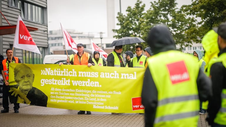 Die Streikenden halten ein Banner mit einem Zitat von Helmut Schmidt, Namensgeber des Hamburger Flughafens: "Natürlich muss auch mal gestreikt werden".