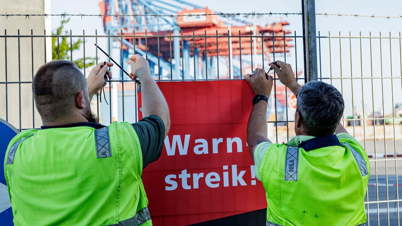 Hafenarbeiter hängen ein Schild mit der Aufschrift „Warnstreik“ auf (Archivbild): Ab Donnerstag soll für 48 Stunden der Betrieb ruhen.