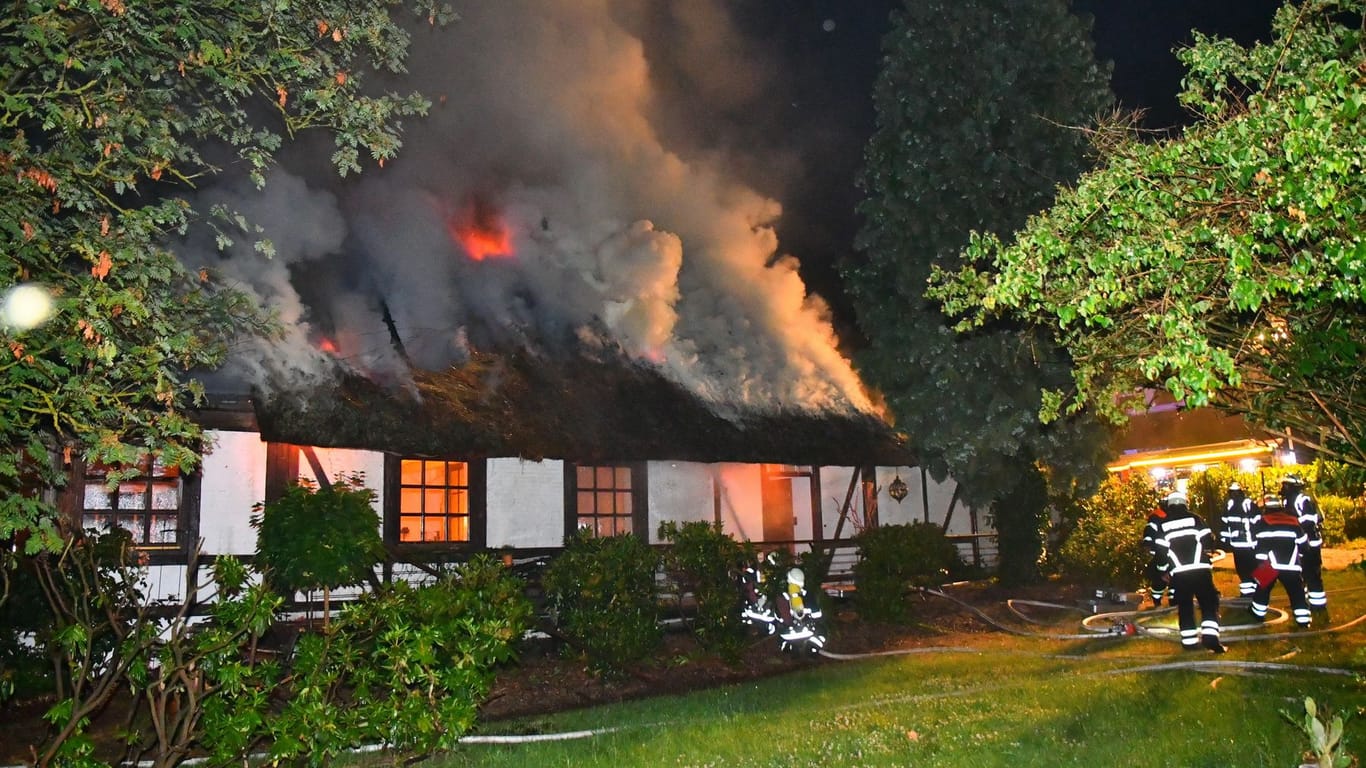 Einsatzkräfte der Feuerwehr vor dem brennenden Reetdachhaus: Es entstand ein Schaden in sechsstelliger Höhe.