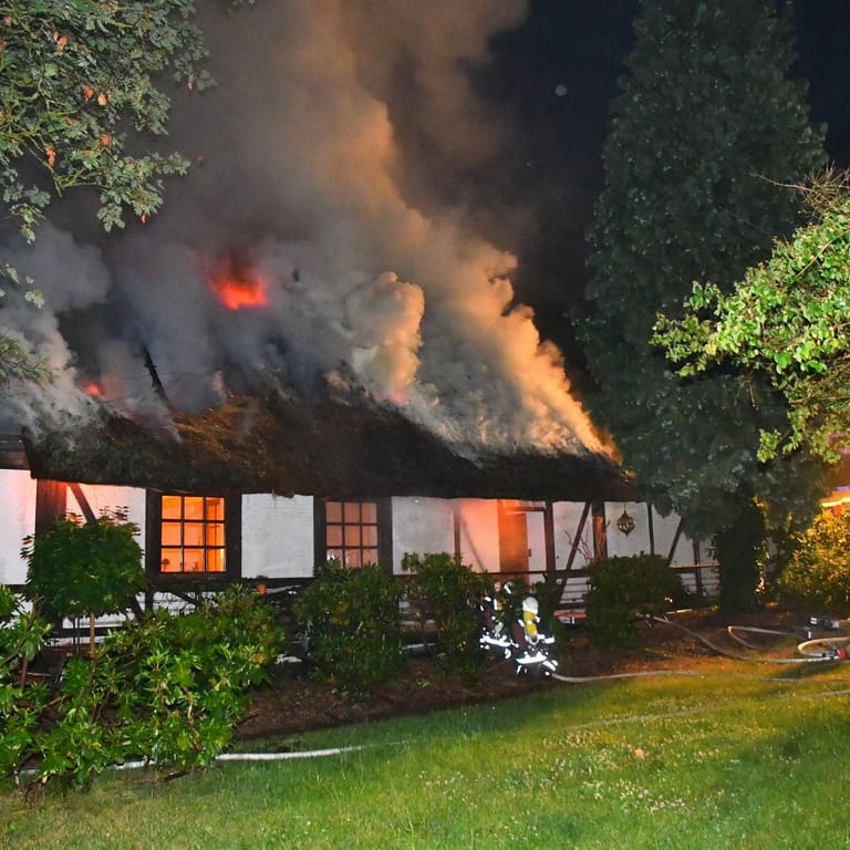 Einsatzkräfte der Feuerwehr vor dem brennenden Reetdachhaus: Es entstand ein Schaden in sechsstelliger Höhe.