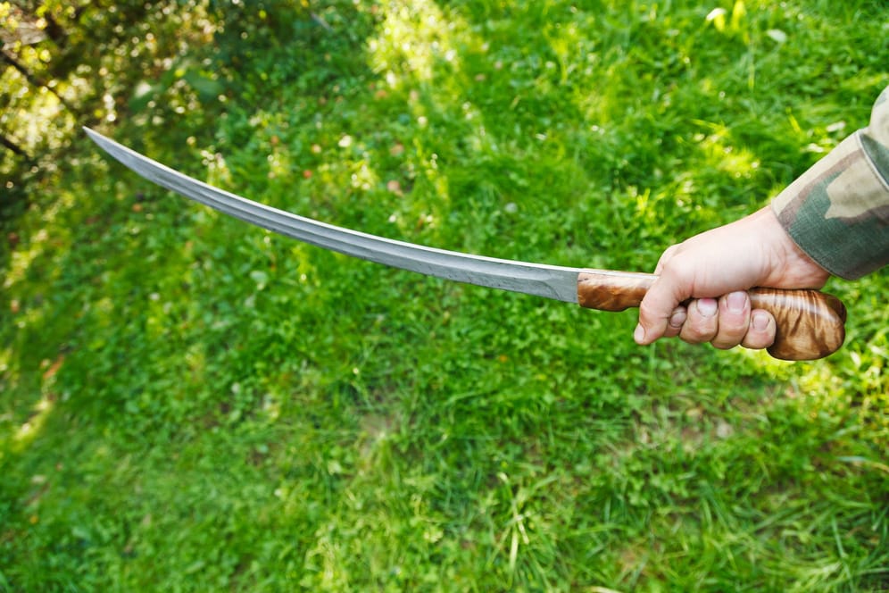 Eine Person hält ein Schwert in der Hand (Archivbild): In Oberhausen soll ein Mann eine Frau mit einem Schwert attackiert haben.