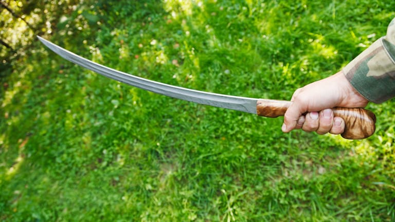 Eine Person hält ein Schwert in der Hand (Archivbild): In Oberhausen soll ein Mann eine Frau mit einem Schwert attackiert haben.