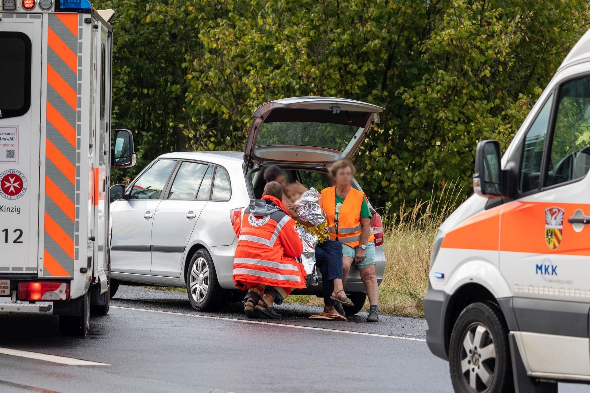 Befreit: Feuerwehrmänner bergen ein Kind aus dem Kofferraum eines Autos.