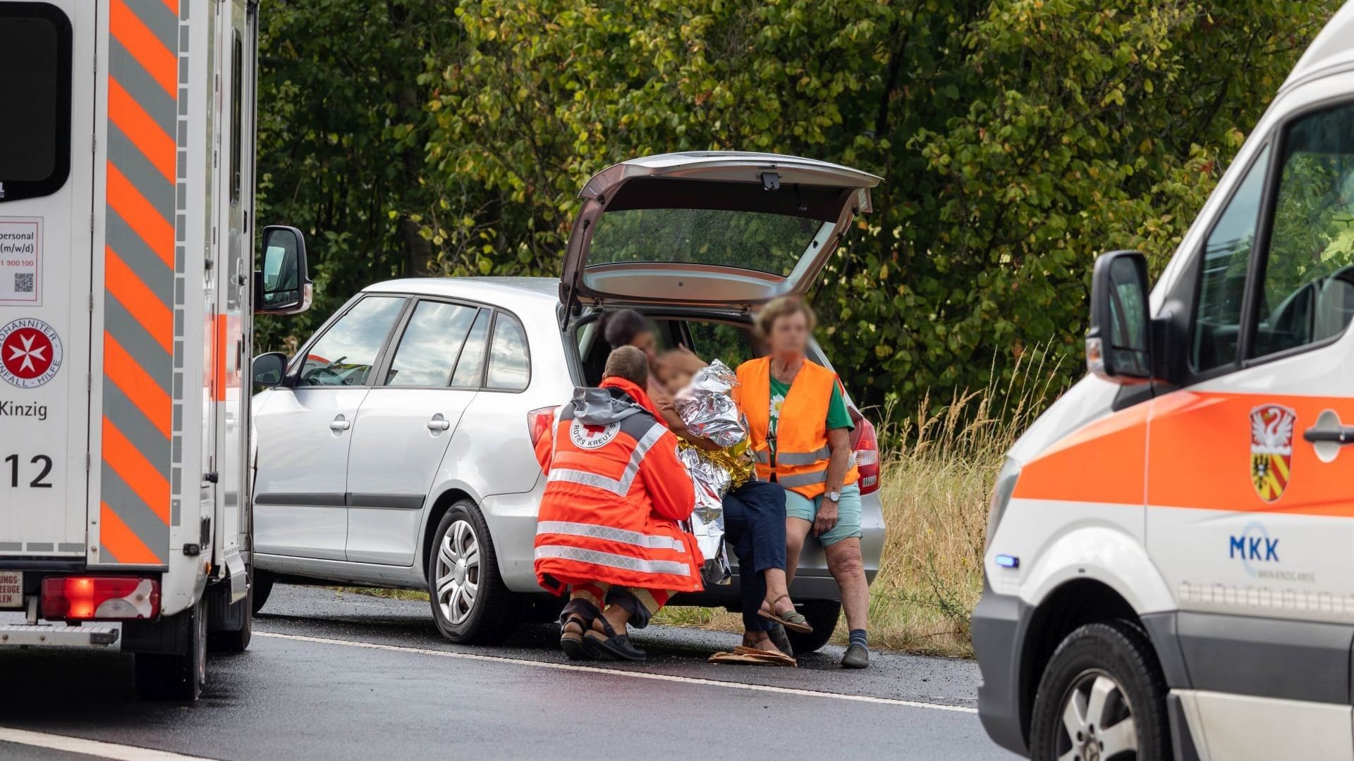 Befreit: Feuerwehrmänner bergen ein Kind aus dem Kofferraum eines Autos.