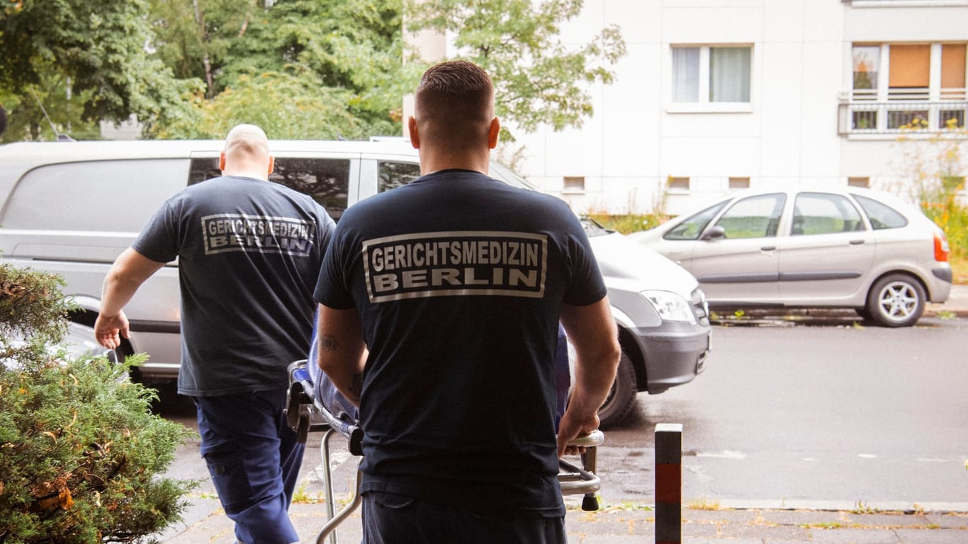 Mitarbeiter der Gerichtsmedizin transportieren die Leiche zu ihrem Wagen: Der Fundort befindet sich nahe dem Strausberger Platz.