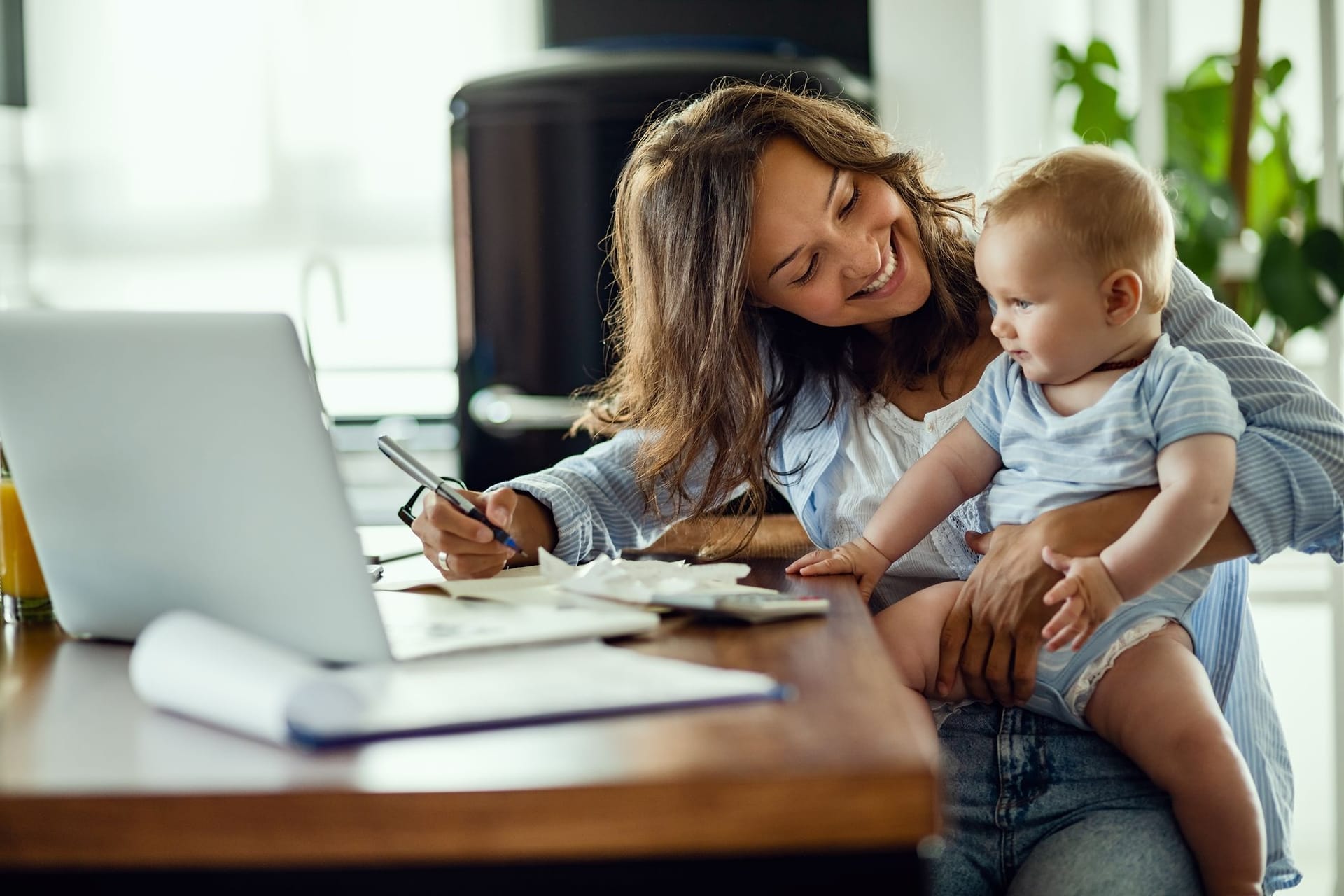 Mutter arbeitet mit Kleinkind auf dem Schoß (Symbolbild): Vor allem viele Frauen arbeiten in Midijobs, um mehr Zeit für die Familie zu haben.