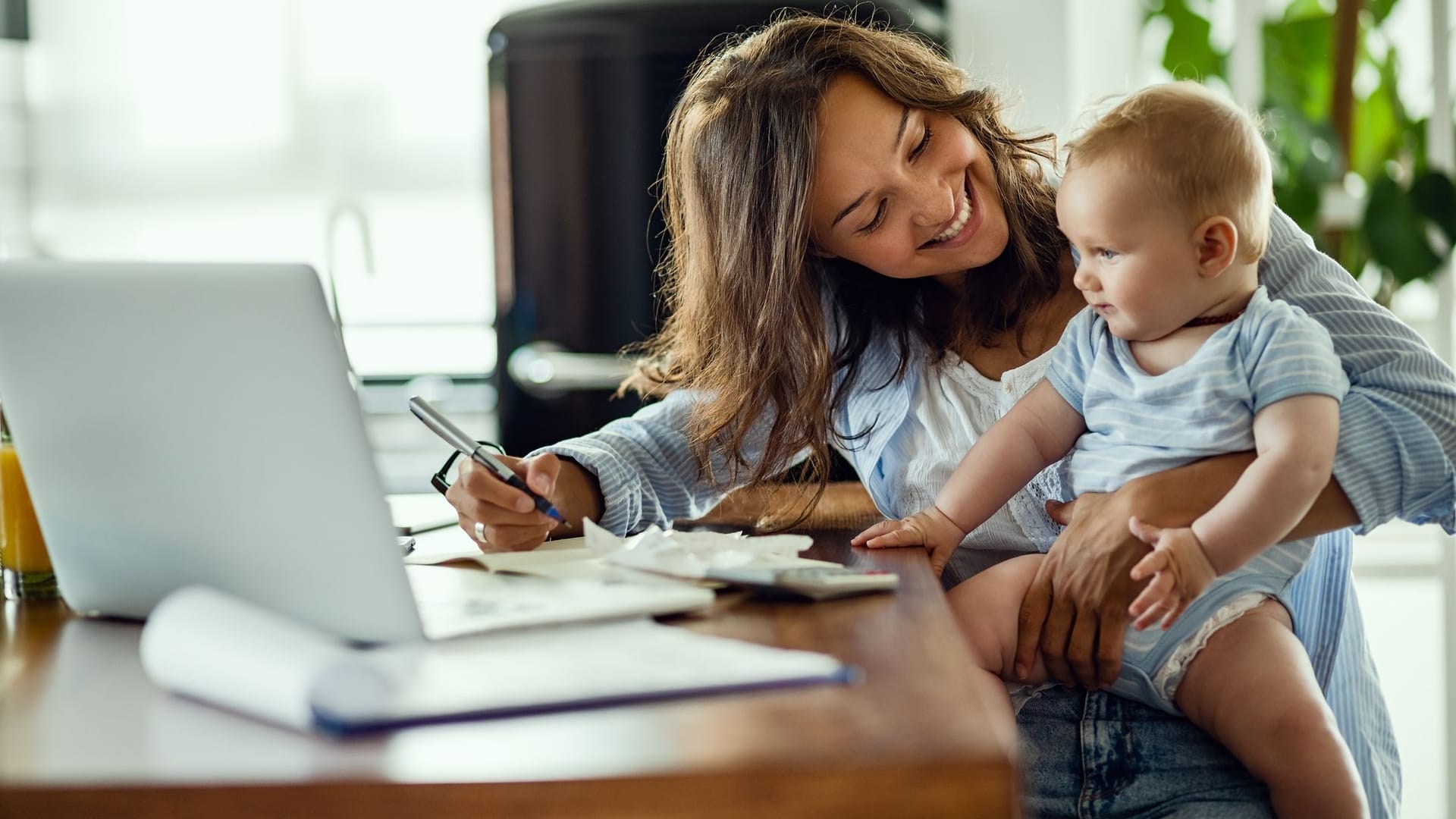 Mutter arbeitet mit Kleinkind auf dem Schoß (Symbolbild): Vor allem viele Frauen arbeiten in Midijobs, um mehr Zeit für die Familie zu haben.