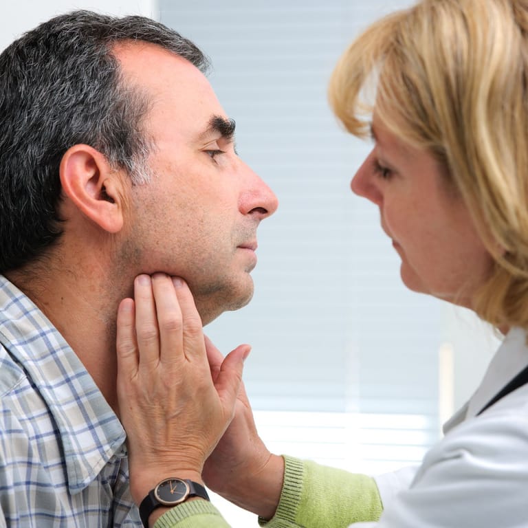 Ärztin tastet die Lymphknoten am Hals eines Patienten ab.