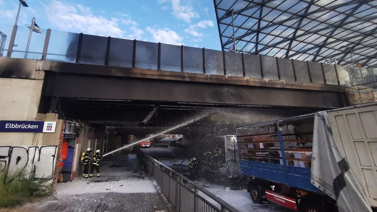 Feuerwehrleute löschen am Bahnhof Elbbrücken einen brennenden Lkw: Wegen des Lastwagen-Brandes unter der Zugbrücke in Hamburg kommt es zu Einschränkungen im Bahnverkehr.
