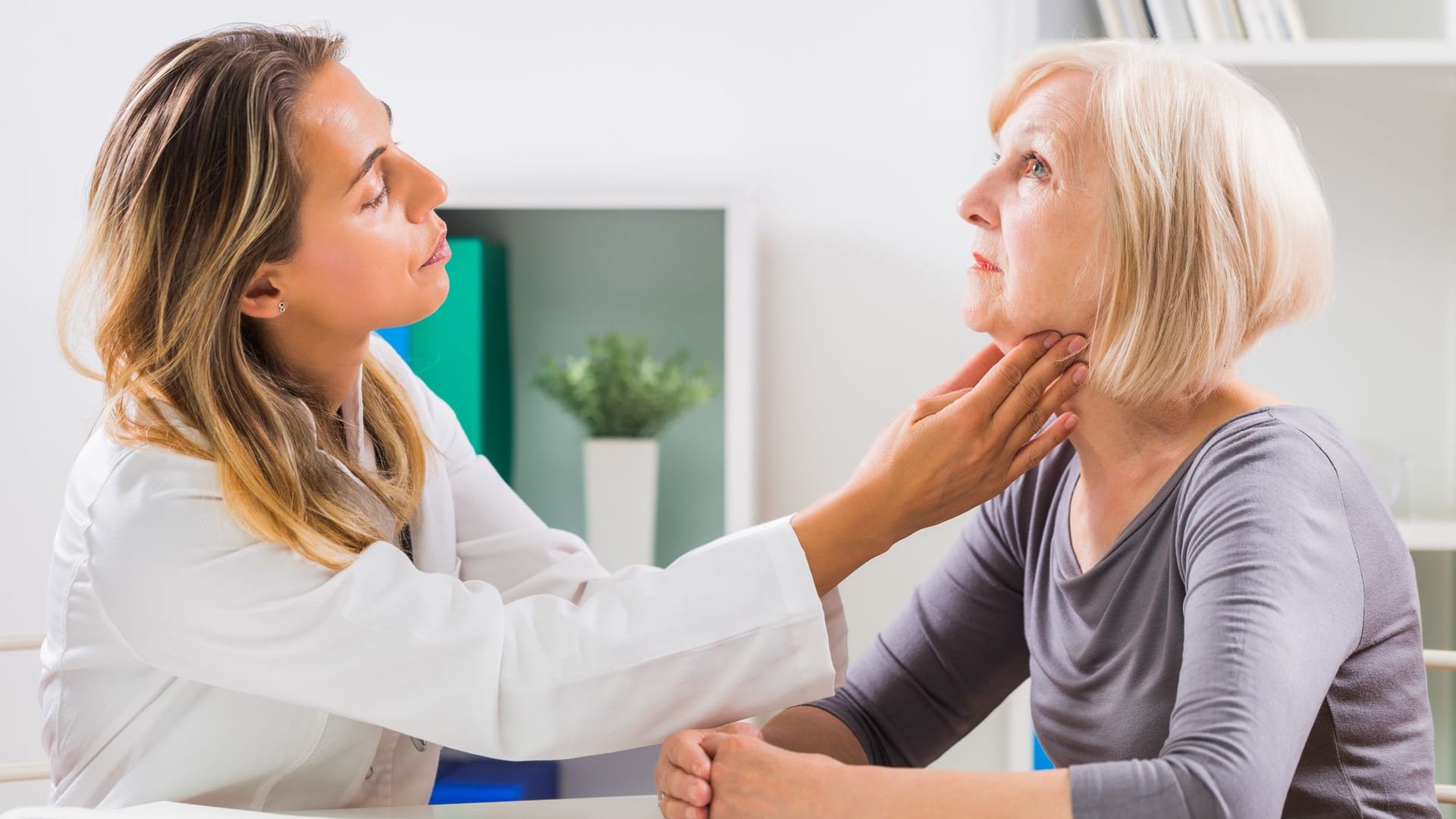 Ärztin tastet bei einer Patientin den Hals ab.