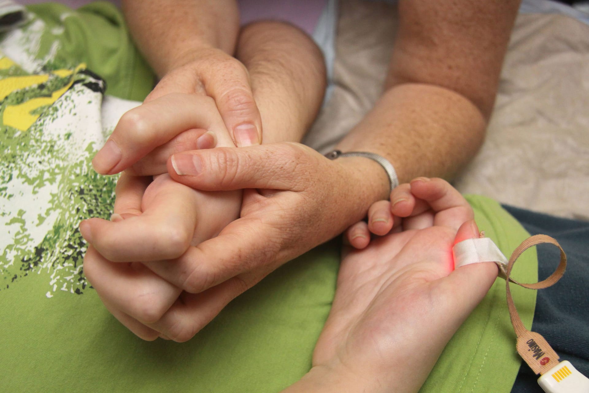 Eine Frau hält im Kinderhospiz Löwenherz die Hand ihres Kindes: Das Hospiz muss wegen Personalnot sein Angebot einschränken.