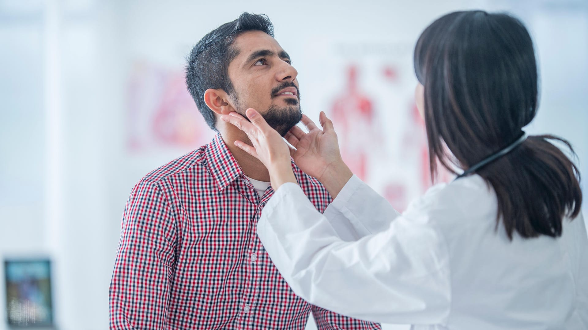 Ärztin untersucht die Lymphknoten am Hals eines Patienten.